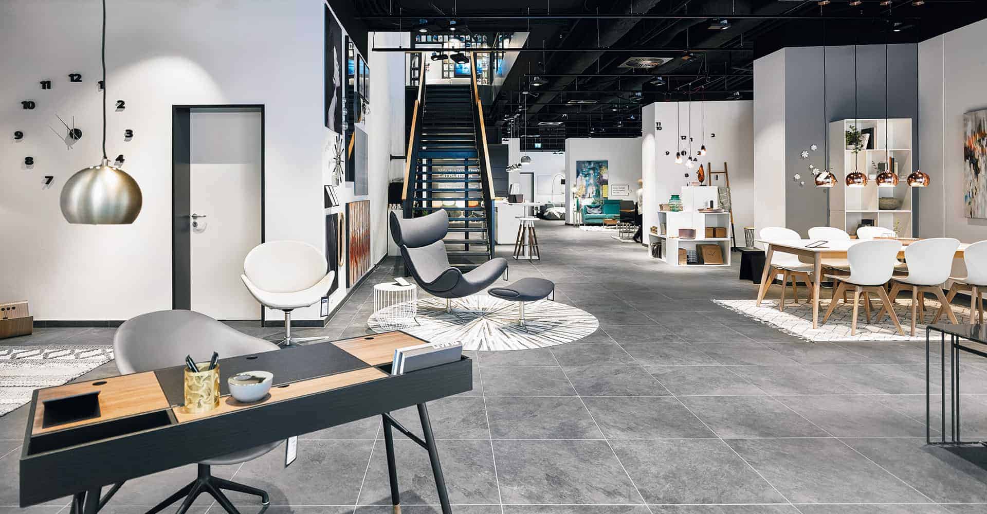 BOCONCEPT STORE DRESDEN | MODERNER INNENAUSBAU FÜR DESIGNERMÖBEL | Innenausbau auf über 2 Etagen in bester Lage am Dresdner Altmarkt nach Vorlage des Corporate Design von BoConcept. Wir hatten nur 10 Wochen Zeit um insgesamt 725 m² Ladengschäft in der Dresdner Innenstadt umzubauen. Die bestehende Gewerbefläche wurde dabei, samt Rolltreppe, zurück gebaut um einen besonderen Rahmen für dänische Designermöbel zu schaffen. Die eigentlich unsichtbare Infrastruktur von Elektro, Lüftung, Sanitär und Klima wurde nun sichtbar in der Decke inszeniert. Eine freitragende Stahltreppe wurde neu integriert.