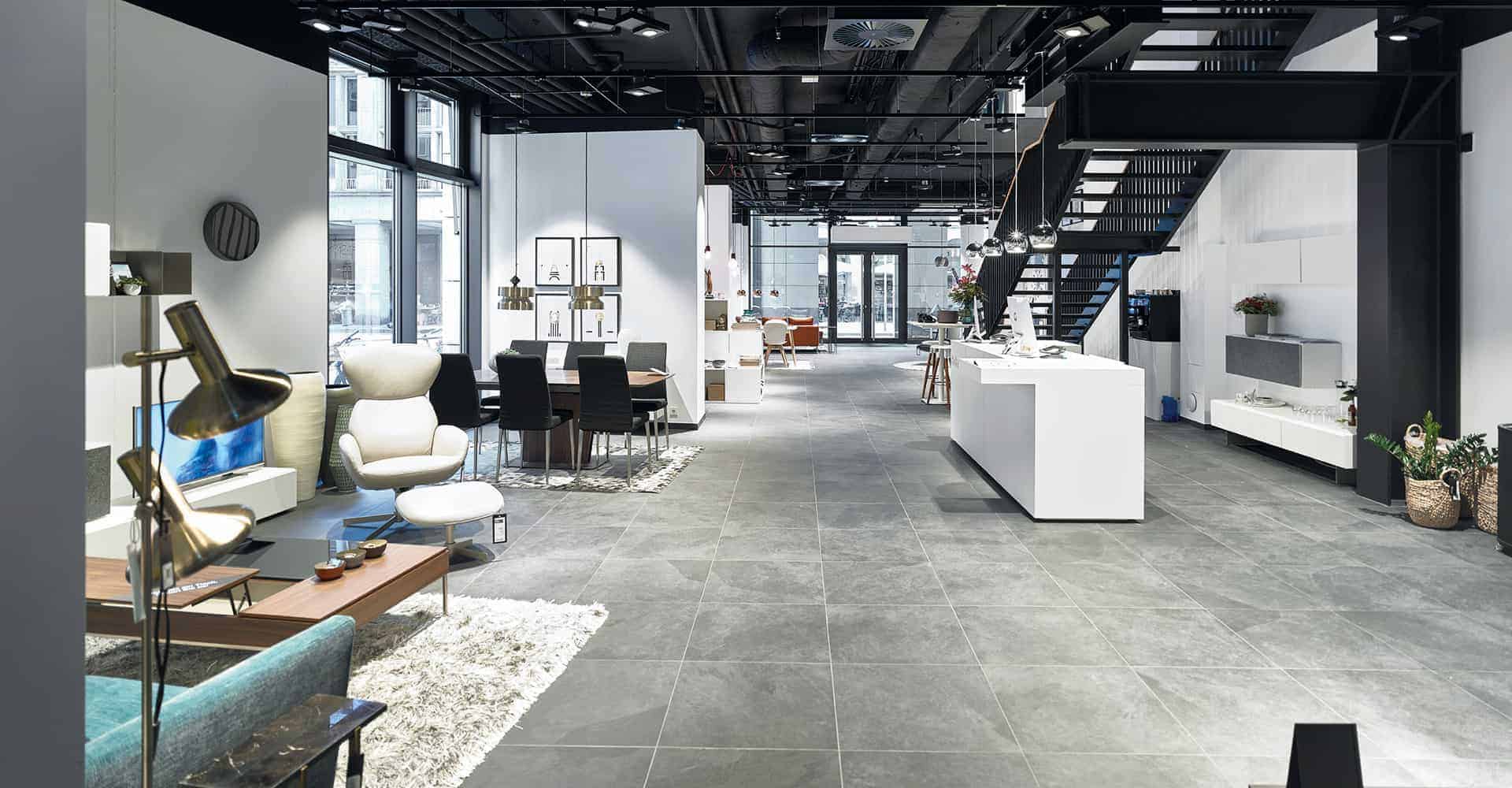 BOCONCEPT STORE DRESDEN | MODERNER INNENAUSBAU FÜR DESIGNERMÖBEL | Innenausbau auf über 2 Etagen in bester Lage am Dresdner Altmarkt nach Vorlage des Corporate Design von BoConcept. Wir hatten nur 10 Wochen Zeit um insgesamt 725 m² Ladengschäft in der Dresdner Innenstadt umzubauen. Die bestehende Gewerbefläche wurde dabei, samt Rolltreppe, zurück gebaut um einen besonderen Rahmen für dänische Designermöbel zu schaffen. Die eigentlich unsichtbare Infrastruktur von Elektro, Lüftung, Sanitär und Klima wurde nun sichtbar in der Decke inszeniert. Eine freitragende Stahltreppe wurde neu integriert.