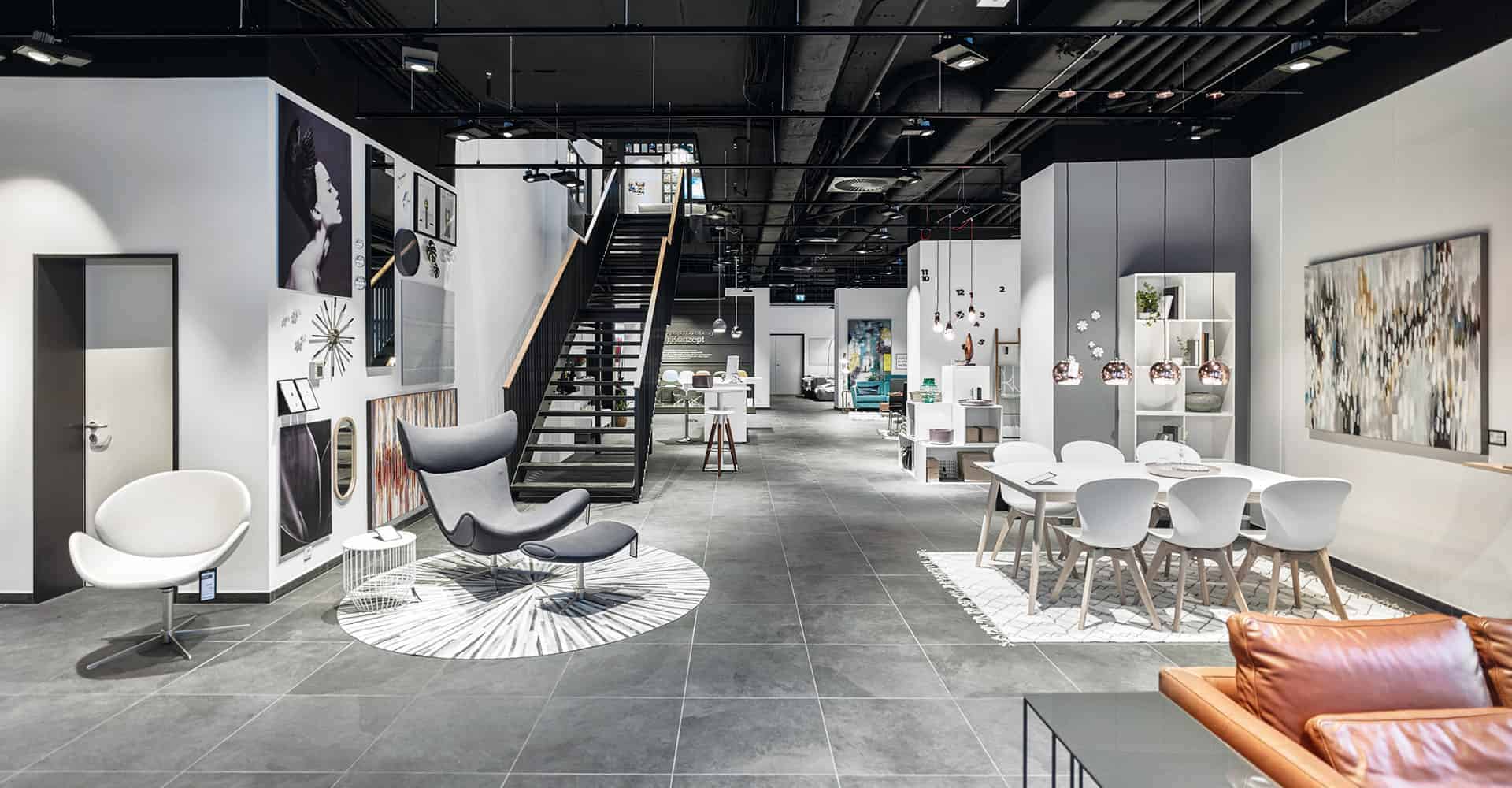 BOCONCEPT STORE DRESDEN | MODERNER INNENAUSBAU FÜR DESIGNERMÖBEL | Innenausbau auf über 2 Etagen in bester Lage am Dresdner Altmarkt nach Vorlage des Corporate Design von BoConcept. Wir hatten nur 10 Wochen Zeit um insgesamt 725 m² Ladengschäft in der Dresdner Innenstadt umzubauen. Die bestehende Gewerbefläche wurde dabei, samt Rolltreppe, zurück gebaut um einen besonderen Rahmen für dänische Designermöbel zu schaffen. Die eigentlich unsichtbare Infrastruktur von Elektro, Lüftung, Sanitär und Klima wurde nun sichtbar in der Decke inszeniert. Eine freitragende Stahltreppe wurde neu integriert.