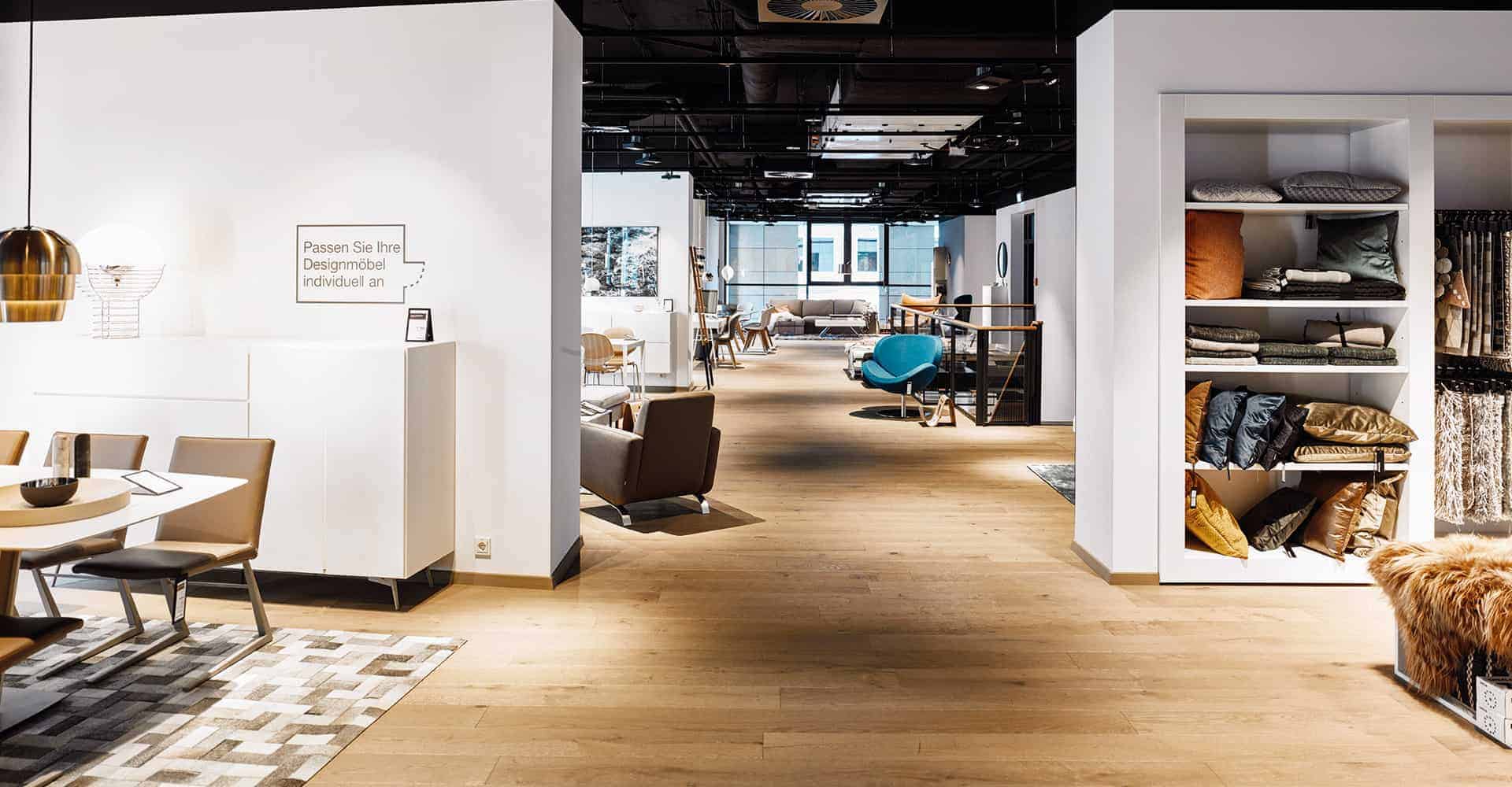 BOCONCEPT STORE DRESDEN | MODERNER INNENAUSBAU FÜR DESIGNERMÖBEL | Innenausbau auf über 2 Etagen in bester Lage am Dresdner Altmarkt nach Vorlage des Corporate Design von BoConcept. Wir hatten nur 10 Wochen Zeit um insgesamt 725 m² Ladengschäft in der Dresdner Innenstadt umzubauen. Die bestehende Gewerbefläche wurde dabei, samt Rolltreppe, zurück gebaut um einen besonderen Rahmen für dänische Designermöbel zu schaffen. Die eigentlich unsichtbare Infrastruktur von Elektro, Lüftung, Sanitär und Klima wurde nun sichtbar in der Decke inszeniert. Eine freitragende Stahltreppe wurde neu integriert.